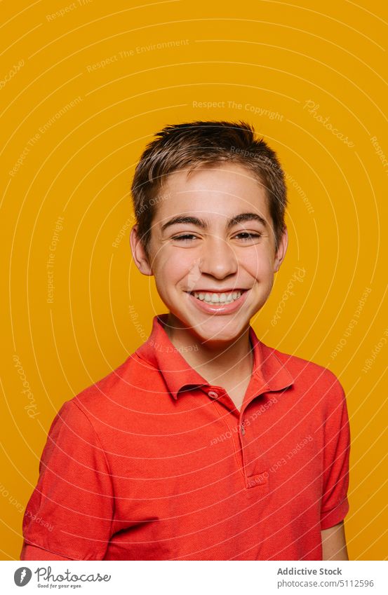 Fröhlicher Junge lächelt und schaut in die Kamera auf gelbem Hintergrund Glück heiter Lächeln Freude hell positiv froh lebhaft Optimist pulsierend Stil lässig