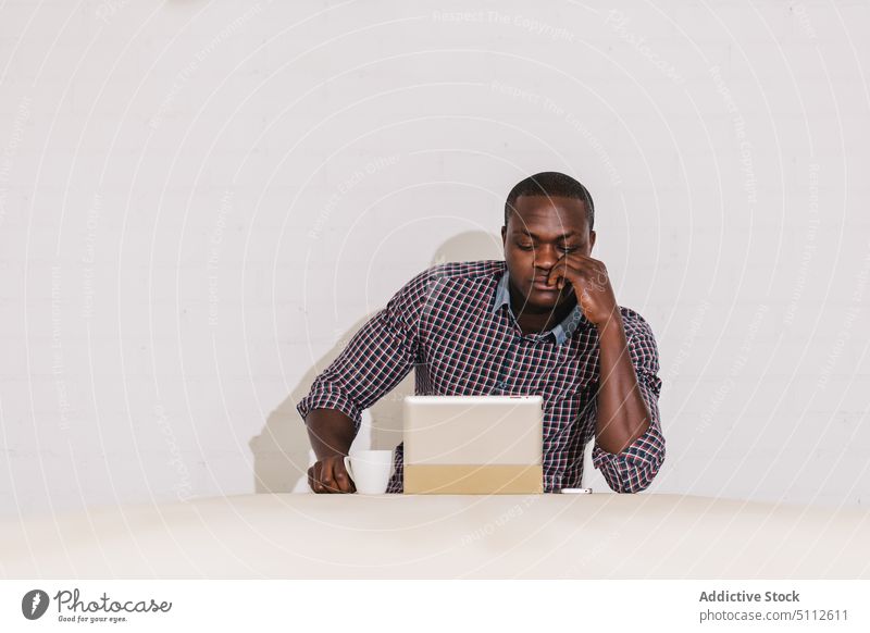Nachdenklicher schwarzer Mann bei der Arbeit mit einem digitalen Tablet auf einem Holztisch Büro Business männlich Geschäftsmann Glück Erwachsener gutaussehend