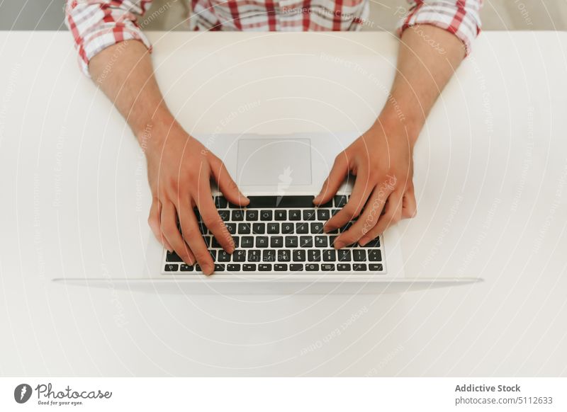 Crop Mann tippt auf einem modernen Laptop Business Schaltfläche Nahaufnahme Computer Datenverarbeitung Schreibtisch Gerät Finger Hand Job Keyboard Tastenfeld