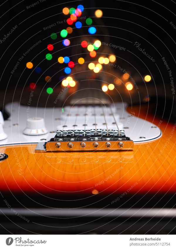 Alte E-Gitarre mit bunter Weihnachtsbeleuchtung als Hintergrund Weihnachten Gesang professionell Geschenke glänzend hölzern Hals festlich Girlande hören Lichter