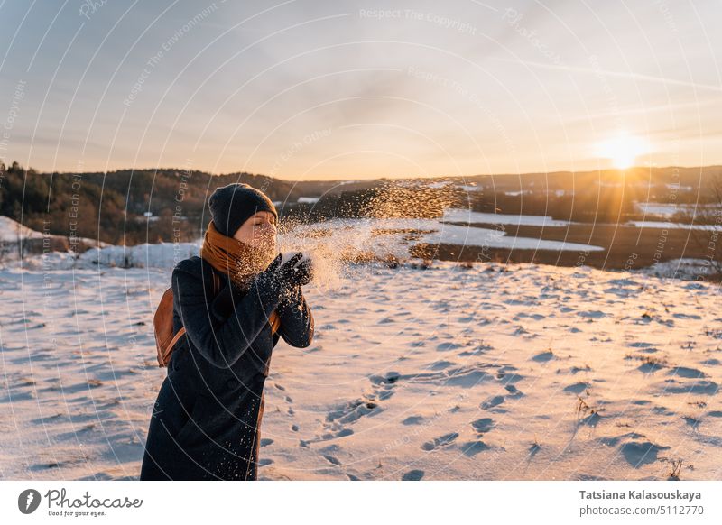 Eine Frau bläst im Winter auf einem schneebedeckten Feld den Schnee von ihren Handflächen Schlag Menschen Person Europäer weiß Erwachsener Halt