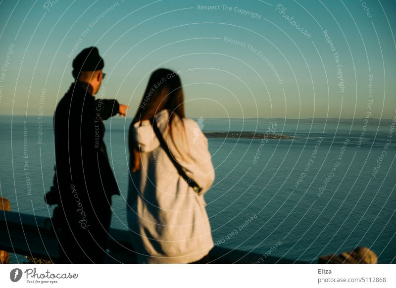 Paar im Urlaub, Mann zeigt aufs Meer zeigen blau zwei beobachten Wasser Menschen schwarz Ferien & Urlaub & Reisen Weite Horizont Küste Natur Ferne Abenteuer