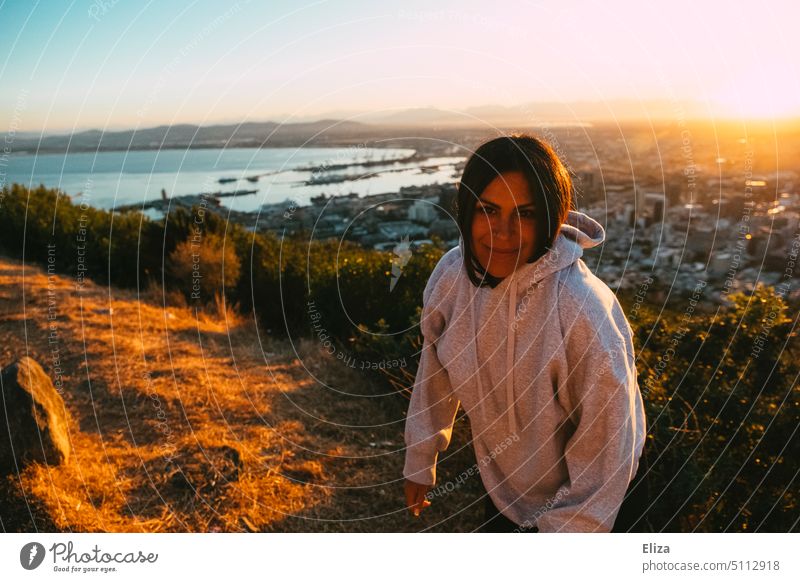 Portrait einer jungen Frau in grauem Kapuzenpulli im Licht der aufgehenden Sonne aufgehende Sonne Hügel Kapstadt Kapuzenpullover Südafrika Morgensonne Natur