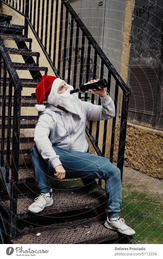 Obdachloser Weihnachtsmann trinkt Wein und durchwühlt Mülltonnen Alkohol alkoholisch böser Weihnachtsmann Vollbart Betteln Flasche brutal Kaukasier Feier
