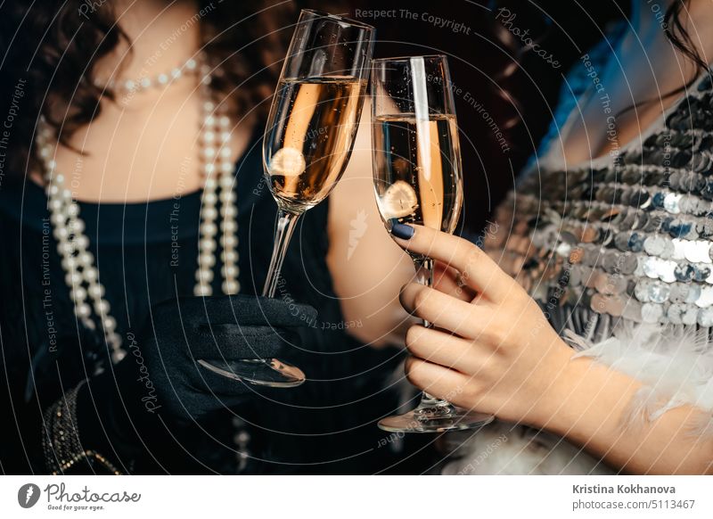 Close up Gläser Champagner. Flappers Frauen tragen im Stil der Roaring Gatsby zwanziger Jahre trinken Alkohol. Vintage, Retro-Party, Mode, Mädchen Freunde Konzept