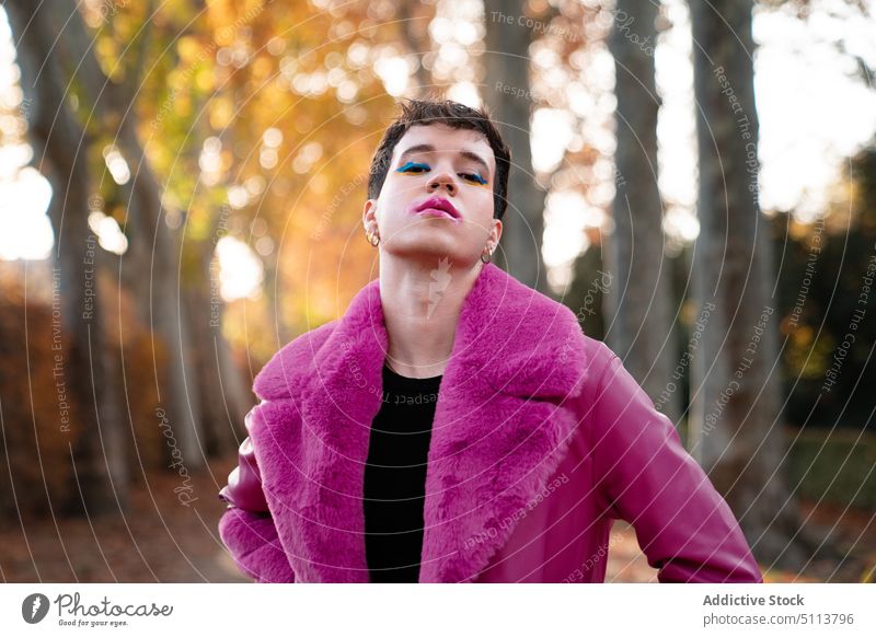 Androgyner Mann mit Make-up im herbstlichen Park stehend androgyn Wald selbstsicher lgbt transsexuell nicht binär Baum Herbst Porträt Homosexualität Geschlecht