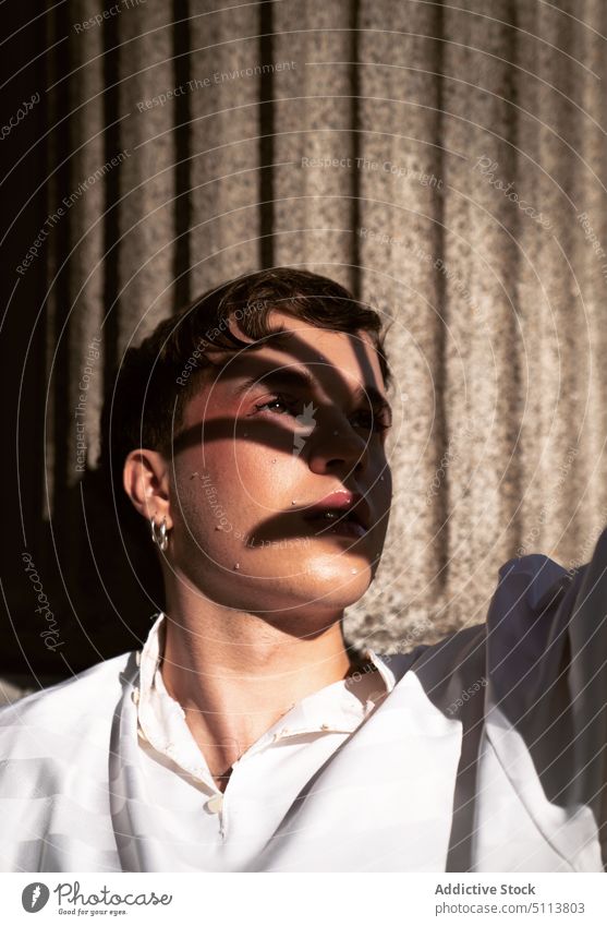 Transsexueller Mann bedeckt Gesicht vor hellem Sonnenlicht transsexuell Deckblatt lgbt Windstille queer androgyn nicht binär verträumt Individualität