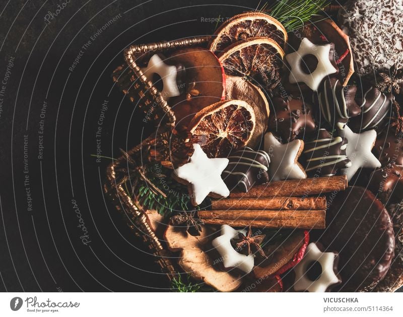 Verschiedene Weihnachten Lebkuchen, Kekse, Süßigkeiten mit getrockneten Orangen und Zimtstangen in Fach auf dunklen Tisch. Köstliche traditionelle Weihnachtssüßigkeiten und -geschmack. Ansicht von oben.