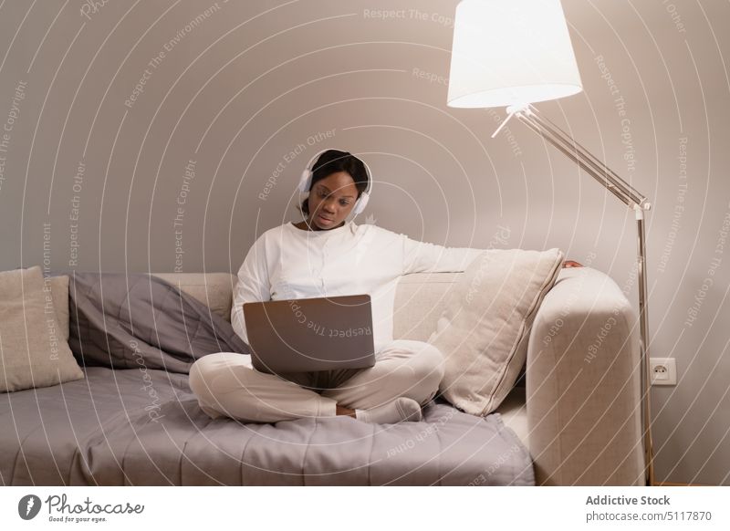 Schwarze Frau benutzt Laptop auf Sofa benutzend Wohnzimmer Film Abend Pyjama Süchtige ruhen schwarz Afroamerikaner ethnisch jung online heimwärts Browsen Liege