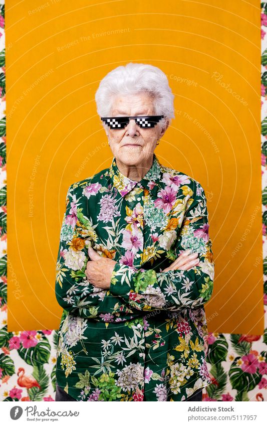 Selbstbewusste ältere Frau mit Pixel-Sonnenbrille selbstbewusst Stil die Arme verschränkt Vorschein geblümt Ornament farbenfroh hell Porträt Senior gealtert