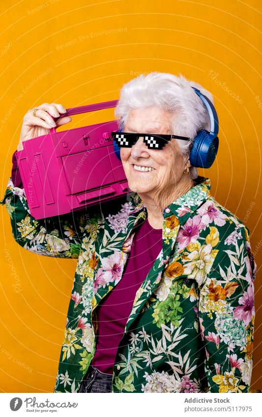 Optimistischer älterer Meloman mit Boombox Frau Lächeln zuhören Musik Stil führen Glück farbenfroh hell Senior gealtert Rentnerin in den Ruhestand gehen