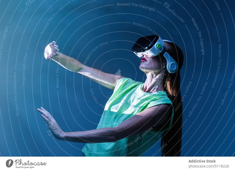 Frau spielt VR-Spiel in Neonlicht Videospiel Virtuelle Realität Headset neonfarbig spielen Rauch Schutzbrille Licht unterhalten Innovation Erfahrung