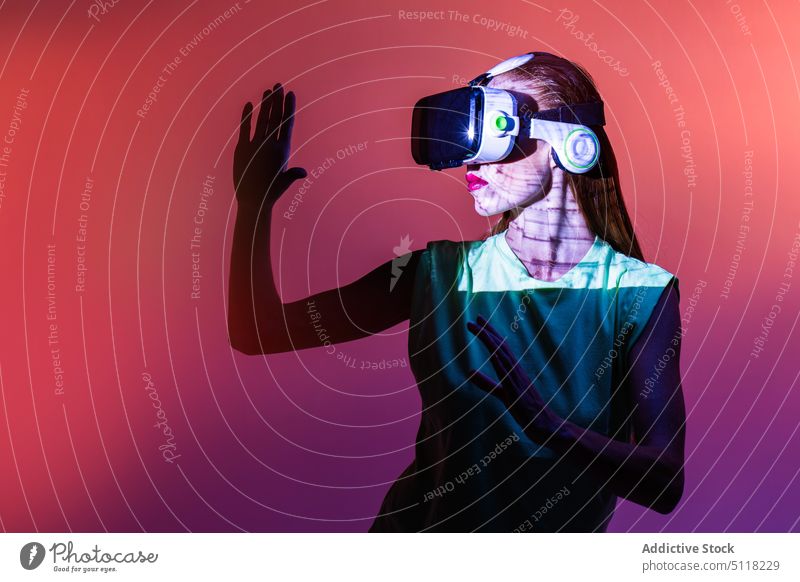 Frau spielt VR-Spiel in Neonlicht Videospiel Virtuelle Realität Headset neonfarbig spielen Schutzbrille Licht unterhalten Innovation Erfahrung