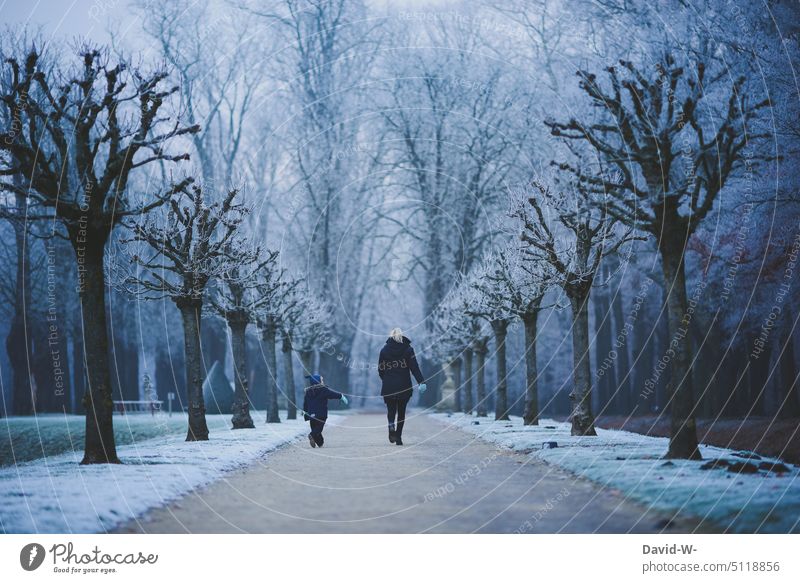 Mutter und Kind machen einen winterlichen Spaziergang Mutter mit Kind Wintertag zusammen gemeinsam Eltern Winterzeit kühl kalt