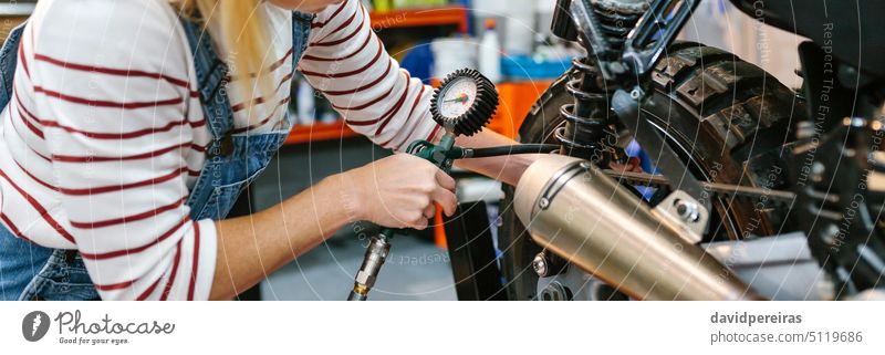 Mechanikerin prüft den Luftdruck der Motorradreifen unkenntlich Frau Überprüfung Air Druck Reifen Rad Manometer arbeiten Fabrik Garage Transparente Panorama