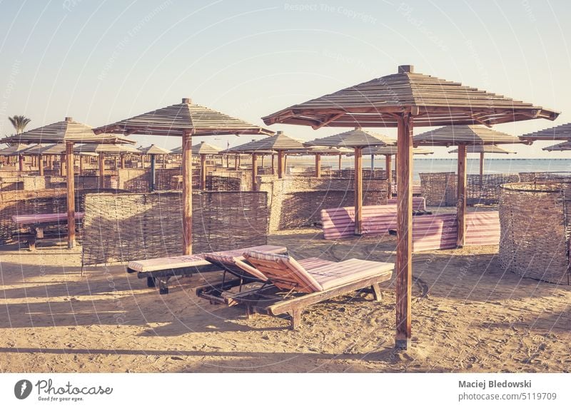 Retro-Foto mit Holzbetten und Sonnenschirmen an einem tropischen Strand. Sand Natur Stuhl Regenschirm Himmel retro altehrwürdig Urlaub MEER Sommer Insel Bett