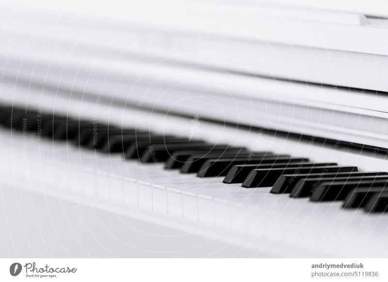 Nahansicht von glänzenden schwarzen und weißen Klaviertasten mit der Reflexion des weißen Randes aus niedrigem Winkel mit geringer Schärfentiefe. selektiver Fokus