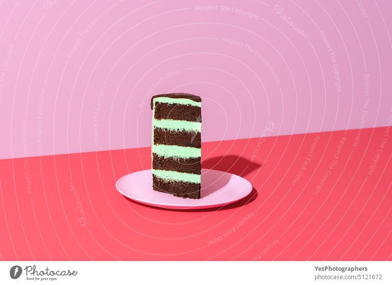 Slice of cake minimalistisch auf einem roten Hintergrund. Schokolade und Minze geschichteten Kuchen. Transparente Geburtstag schwarz hell Buttercreme Feier