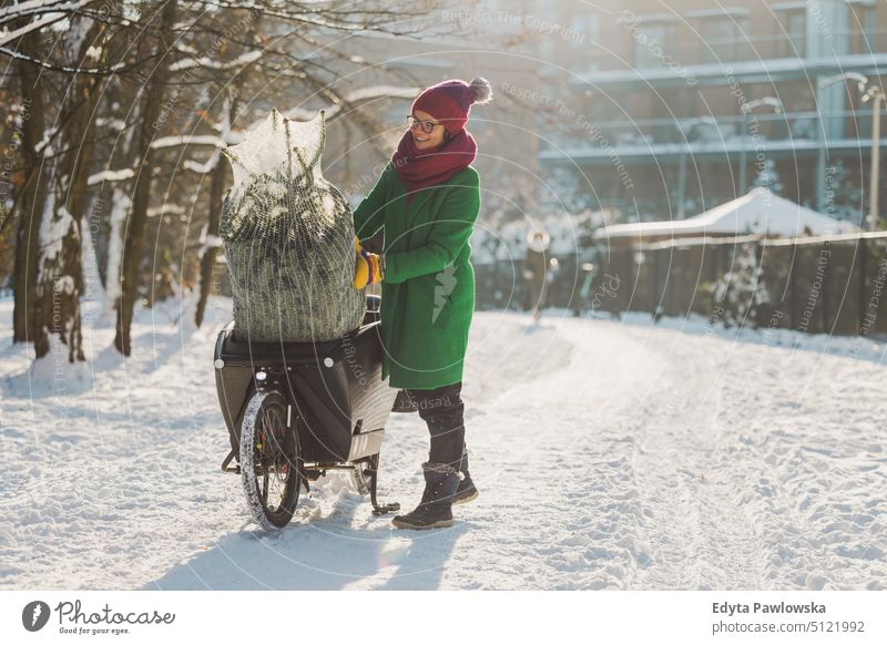 Frau transportiert Weihnachtsbaum auf Lastenfahrrad nachhaltiger Transport transportierend ökologisch Ökologie Kohlenstoff-Fußabdruck umweltfreundlich Lastenrad