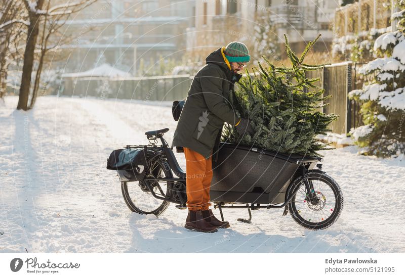Mann transportiert Weihnachtsbaum auf Lastenfahrrad nachhaltiger Transport transportierend ökologisch Ökologie Kohlenstoff-Fußabdruck umweltfreundlich Lastenrad