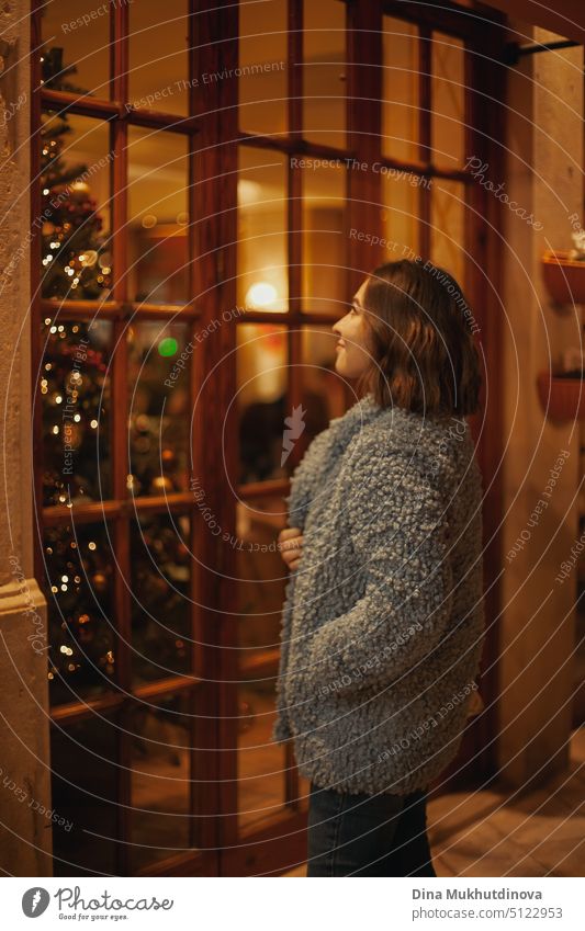 Lächelnde Frau, die vor einem Café steht und einen Weihnachtsbaum betrachtet. Magic Winter Urlaub Saison Ambiente. schön Baum Feiertag Hintergrund Glück Mädchen