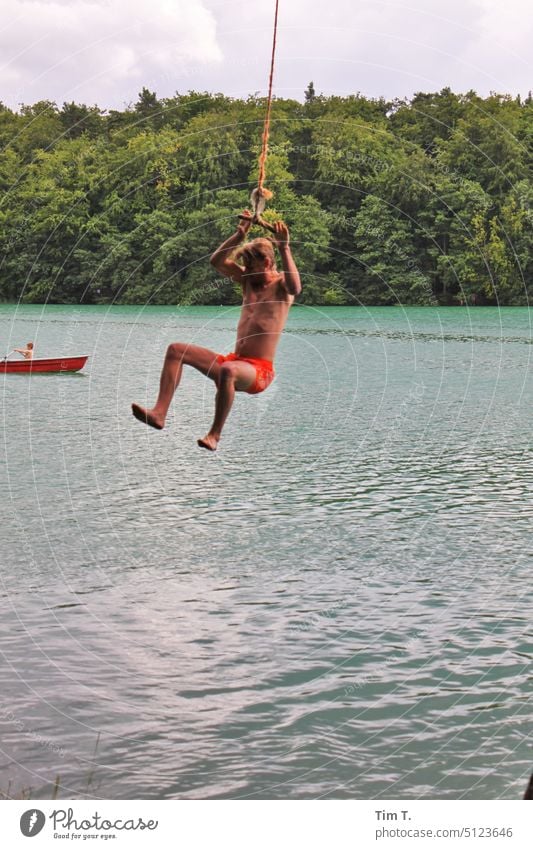 Mann schwingt an einem Seil über dem See Sommer Brandenburg liepnitzsee Schaukel schwingen Außenaufnahme Freude Wasser Farbfoto schaukeln Mensch Lebensfreude
