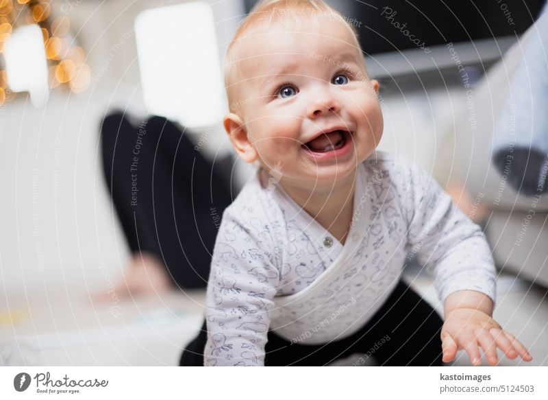 Cute Säugling Baby Junge spielen, krabbeln und aufstehen von Wohnzimmer-Sofa zu Hause. Baby spielt zu Hause neugeboren Kindheit Entwicklung Spielzeug