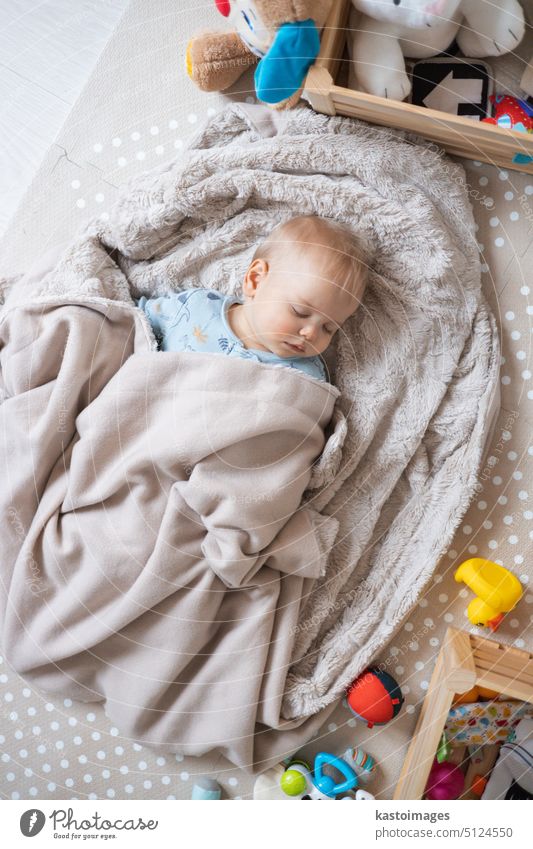 Niedlicher Säugling, der auf einer Spielmatte schläft, bedeckt mit einer warmen, kuscheligen Decke Baby Junge Kaukasier Kindheit Hintergrund wenig weiß Unschuld