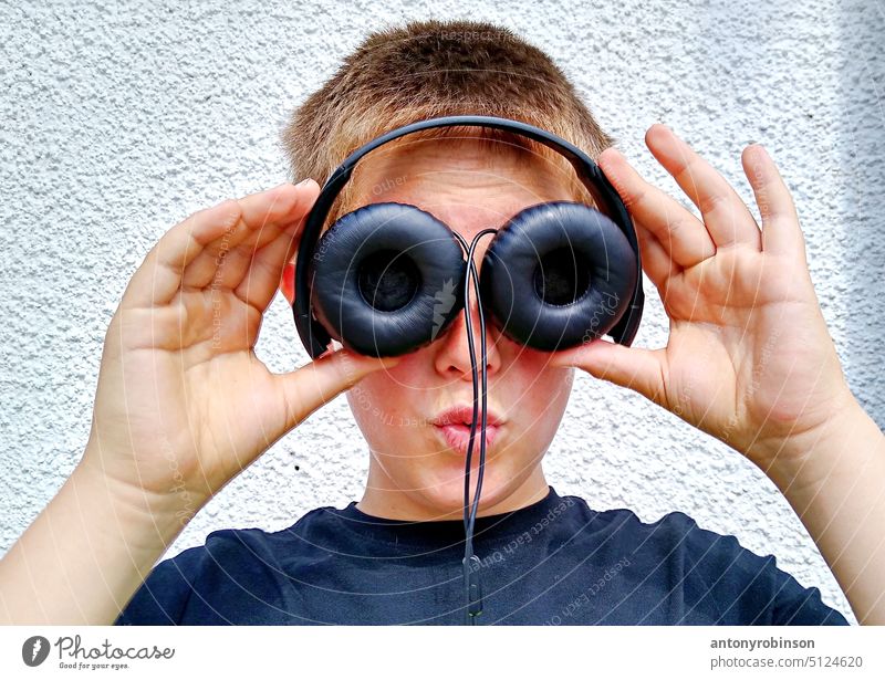 Junge hält sich Kopfhörer vor die Augen Kind spielen Brille Spaß Spielen große Augen