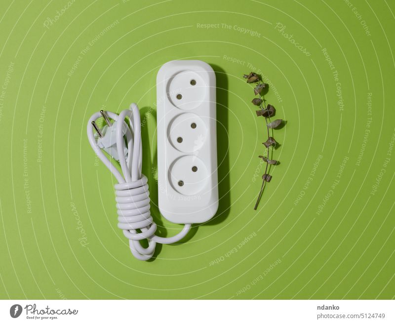 Weiße Kunststoffsteckdose mit Kabel auf grünem Hintergrund, Ansicht von oben Blatt Steckdose Öko Kraft Energie Elektrizität Technik & Technologie Stecker