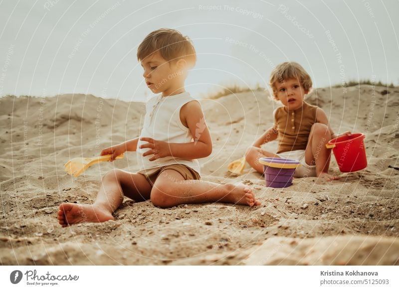 Zwillingsbrüder spielen am Strand im Sand mit ihrem Plastikspielzeug. Sommer sonnigen Tag. Nette Freunde, Kinder, Familie Konzept. Spaß Person Urlaub MEER