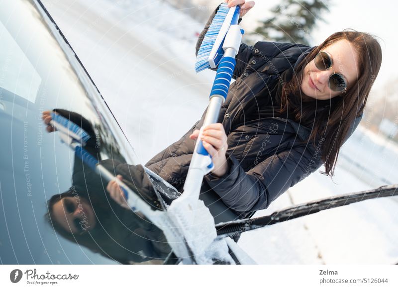 Frau reinigt Auto mit einer Bürste vom Schnee nach einem Schneesturm PKW Reinigen kalt Glas Hand Beteiligung Person Entfernung Sicherheit saisonbedingt