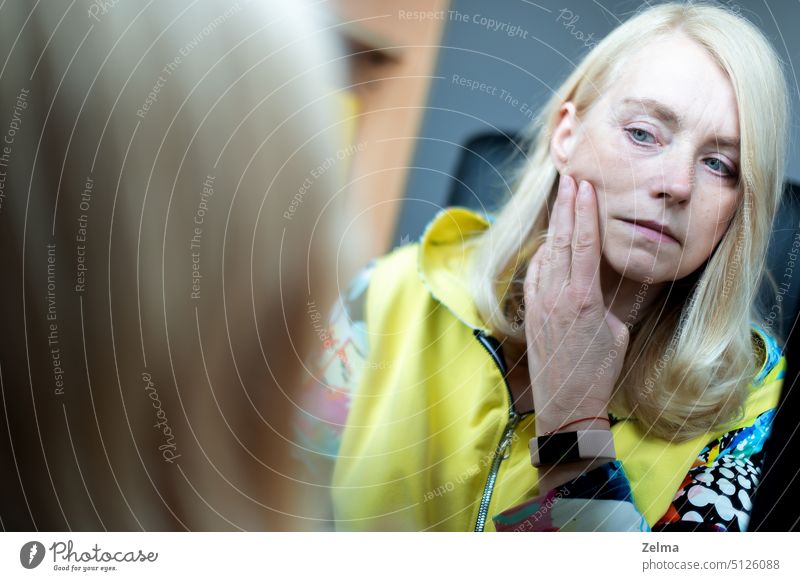 Porträt einer Frau mittleren Alters, die ihr Gesicht im Spiegel betrachtet, Konzept der Hautalterung reif traurig Alterung Schönheit Pflege Überprüfung Falte