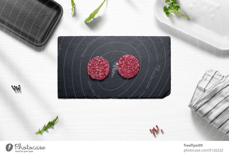 Mini-Hamburger aus Rindfleisch auf einem flachen Küchenbild mit verschiedenen Gegenständen hamburguer Fleisch Spielfigur roh Metzger Werkstatt Textfreiraum