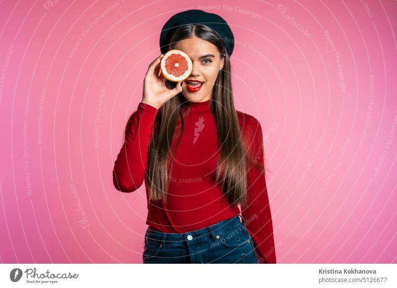 Porträt einer jungen schönen Frau in Rot mit zwei halben saftigen Grapefruits in Rosa Person Zitrusfrüchte Diät vereinzelt Hintergrund frisch Pflege Beteiligung