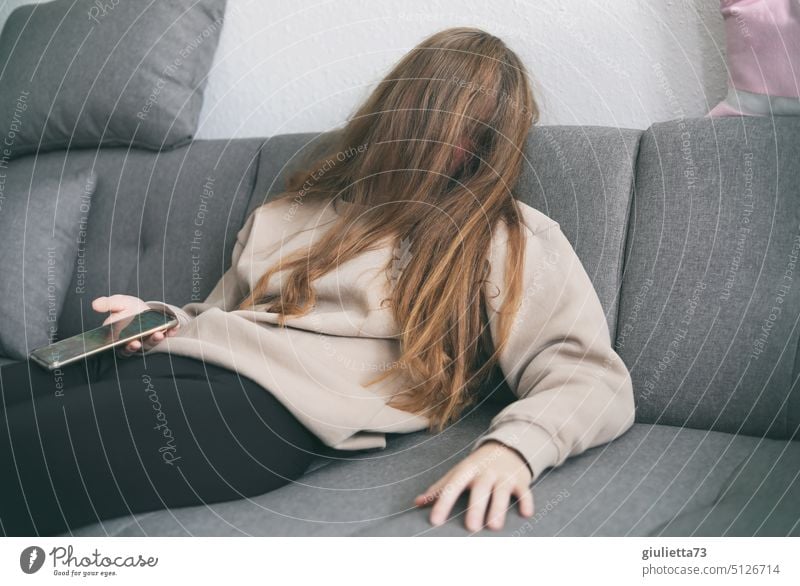Burnout , junge Frau liegt völlig erschöpft auf der Couch, eingeschlafen mit Handy in der Hand Porträt Junge Frau teenager Mädchen 13-18 Jahre Jugendliche