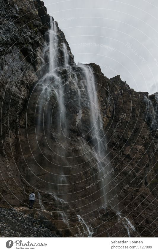 Cirque de Gavarnie mit großem Wasserfall und kleiner Person an massiver hoher Felswandformation in den Pyrenäen, Nouvelle-Aquitaine, Frankreich Berge u. Gebirge