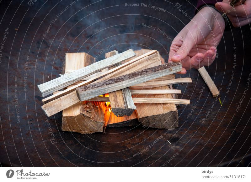 Holzfeuer in einer Feuerschale entfachen Feuerstelle Kleinholz Feuerholz Flamme Hand Rauch