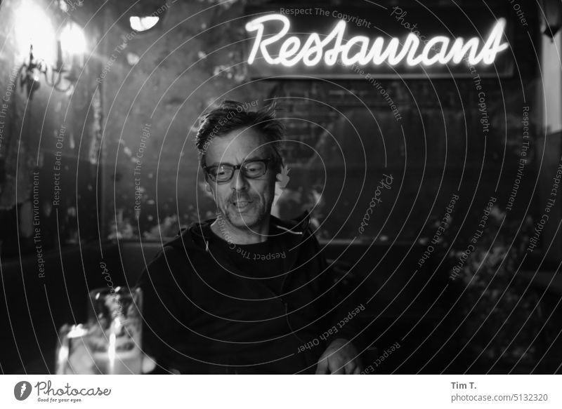 ein Mann mit Brille in einer Kneipe Berlin Prenzlauer Berg s/w Bar Nacht Restaurant Stadt Hauptstadt Stadtzentrum Schwarzweißfoto Innenaufnahme bnw