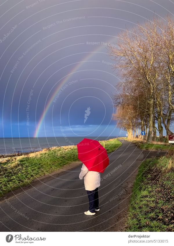 Dame mit rotem Regenschirm bestaunt den Doppelregenbogen in Schleswig-Holstein Panorama (Aussicht) Textfreiraum links Textfreiraum rechts Textfreiraum Mitte