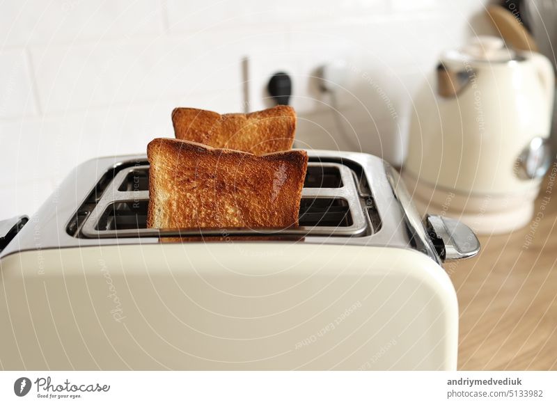 Moderner weißer Toaster und geröstete Brotscheiben, die auf einem Holztisch in der Küche geröstet werden Frühstück Lebensmittel gebraten Vorrichtung Gesundheit