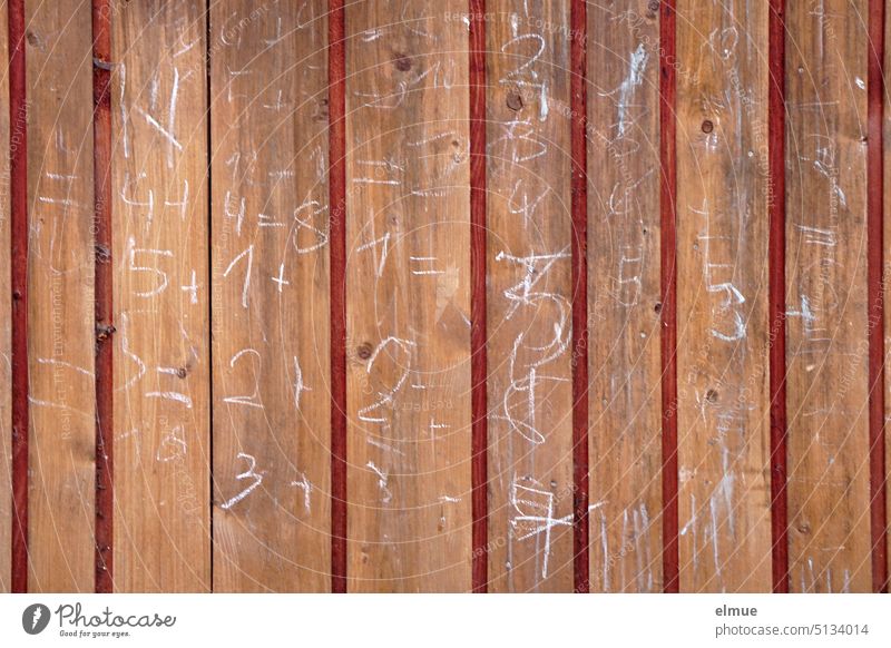 auf einer Holzwand stehen mit weißer Kreide geschriebene Ziffern und Rechenaufgaben Latten Zahlen rechnen Freizeit Schmiererei Spielerei Kinderspiel Kopfrechnen