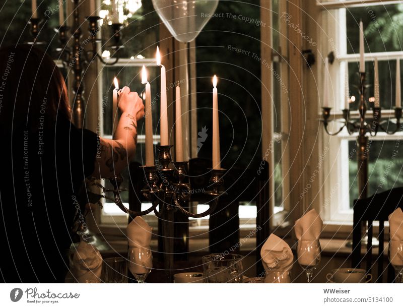 Jemand zündet die Kerzen an einem festlichen Leuchter an, offenbar steht ein feierliches Abendessen bevor Feier Familienfeier leuchten Beleuchtung Romantik