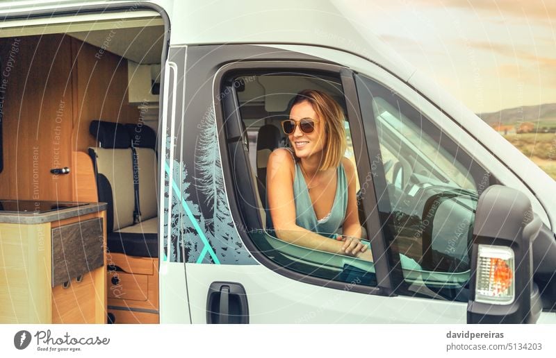 Junge Frau mit Sonnenbrille im Wohnmobil sitzend Lächeln jung Kleintransporter Sitzen Sommer Ausflug reisen Reise Fahrzeug Freiheit 20s Person Tourist PKW Glück