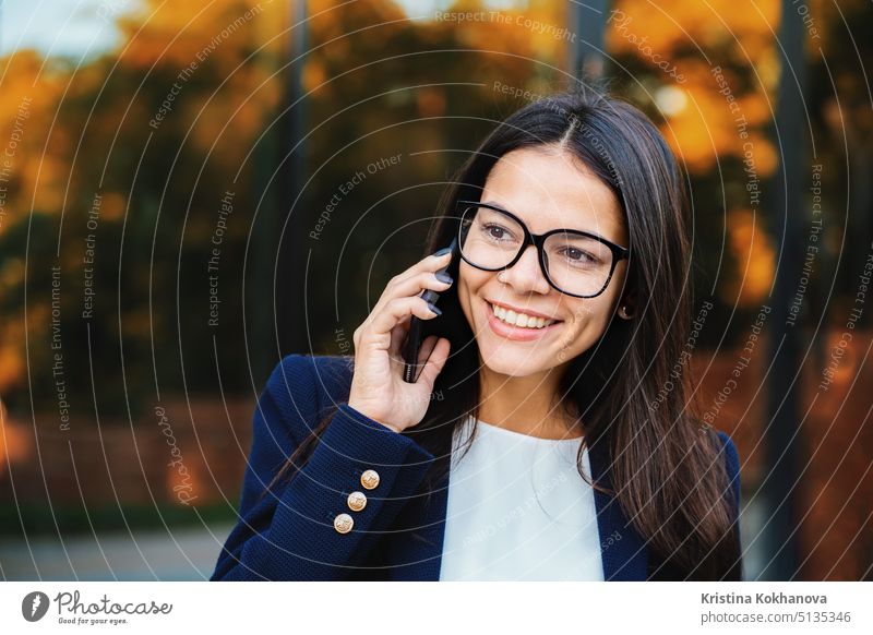Geschäftsfrau unterhält sich mit einem Mobiltelefon. Business-Mädchen in Brillen und formale Anzug fröhlich spricht mit Kollegen. Büroangestellte, Lohnarbeiter, Wochentage Konzept.