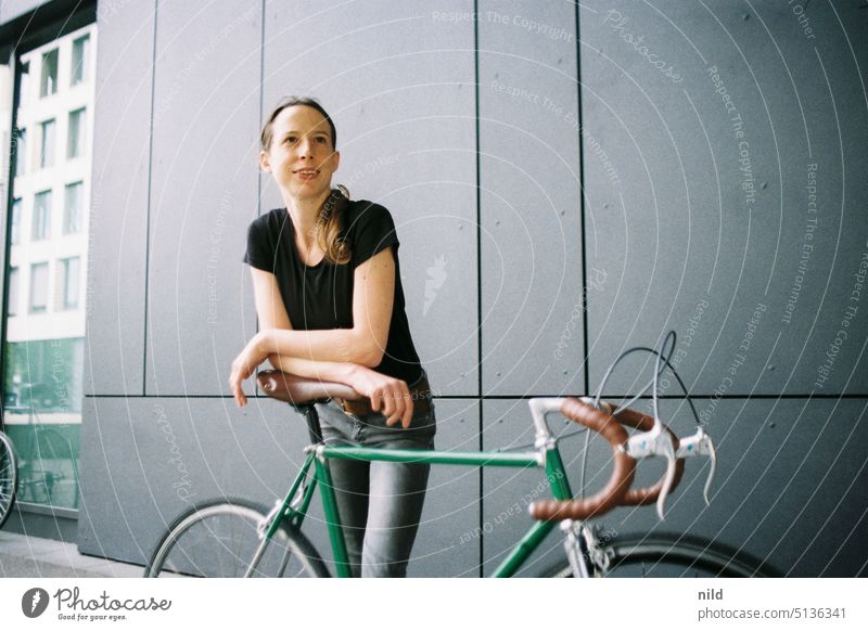Junge Frau mit grünem Vintage-Rennrad vor grauer Wand vintage Singlespeed urban Textfreiraum links Mobilität retro Lifestyle Fahrrad Verkehrsmittel sportlich