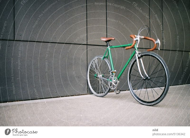Grünes Vintage-Rennrad vor grauer Wand vintage Singlespeed urban Textfreiraum links Mobilität retro Lifestyle Fahrrad Verkehrsmittel sportlich Farbfoto Stadt