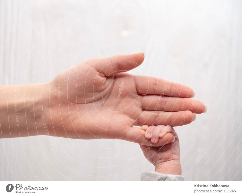 Neugeborenes Baby's Hand hält Finger seiner liebenden Mutter. Konzept der Liebe und Familie. Weißer Hintergrund neugeboren Kind Pflege Kindheit Unschuld winzig