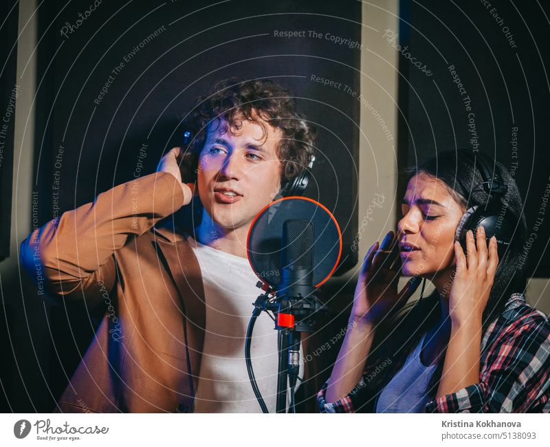Zwei junge Sängerinnen führen ihr Lied im Aufnahmestudio auf. Professionelles Musikerduo bei der Aufnahme einer neuen CD. Schönes Paar arbeitet zusammen.