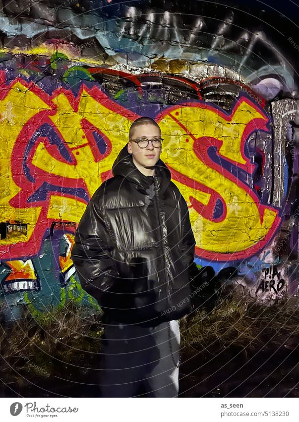 Jugendlicher vor Graffiti Wand im Dunkeln junger Mann Dunkelheit Junger Mann Mensch Außenaufnahme 16 Jahre 18-30 Jahre maskulin Erwachsene Farbfoto Oberkörper